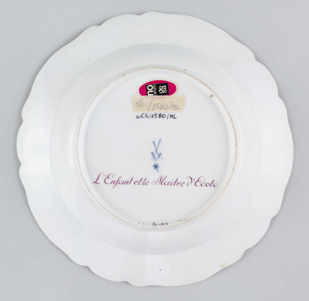 S/CS/1580/ML - Talerz głęboki o falistym wykroju brzegu. Na dnie malowana barwna miniatura przedstawiajaca scenkę w pejzażu: chłopiec wpadł do strumienia i trzyma się gałązki wierzby rosnacej na brzegu, obok stoi nauczyciel z rózgą w ręce. Na kołnierzu malowana mozaika w kolorze zieleni miedziowej, obramowana od środka złotymi rocaille'ami z piecioma rzuconymi gałązkami. 
Na spodzie napis wykonany naszkliwnie purpurą: 