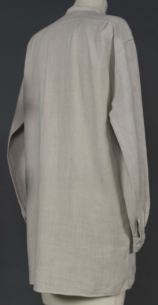 E/7980/ML - Koszula męska z lnianego, szarego płótna. Szyta ręcznie. Kołnierzyk to wąska oszewka z bawełnianego płótna. Z przodu rozcięcie zapinane na 3 guziczki wzmocnione plisą z podwójnego kawałka płótna. Rękawy długie, ujęte w mankiet, zapinany na guziczek. Pod pachami wszyte prostokątne kawałki tkaniny, zw. tokami.