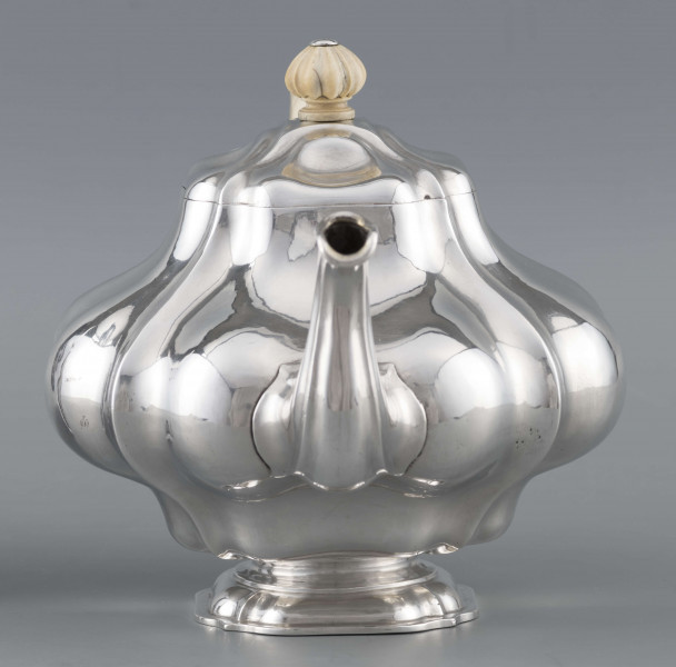 S/Mt/500/ML - Korpus silnie wybrzuszony w części środkowej, puklowany pionowo, profile przechodzą na pokrywke w formie wieczka na zawiasie. Stopa kwadratowa wielolistna, wylew w formie dzióbka, ucho kościane osadzone w dwóch tulejkach,
uchwyt na pokrywce kościany, profilowany. Wnetrze złocone.
Na spodzie stopy sygnatura:
- 