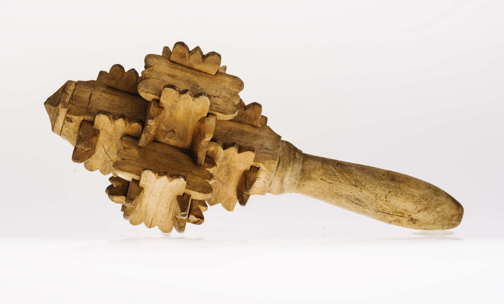 Grzechotka ta składa się z kawałeczków deseczki, rzeźbionych z brzegu i wycinanych w środku z jednej strony. Zrobiona jest bez kleju i gwożdzi. Deseczki te mają wymiary: dł. 4,5 cm szer. 2,2 cm grub. 0,5 cm. Jest ich 26. Tworzą one 6 