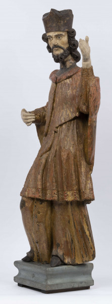 E/16816/ML - Rzeźba drewniana, pełna, polichromowana, przedstawiająca św. Jana Nepomucena. Kompozycja frontalna. Postać stojąca w kontrapoście – prawa noga zgięta i wysunięta do przodu. Sylwetka przechylona na prawo. Lewa ręka zgięta w łokciu i wysunięta do przodu. Prawa zgięta, uniesiona do góry. Brak atrybutów (krzyża i palmy) w dłoniach.
Postać ubrana w sutannę, komżę drapowaną w fałdy i zakończoną koronką, płaszcz z kapturem. Ślady złoceń na partii ubrania. Głowa skierowana na prawo. Twarz podłużna (kolor kremowy), usta proste, oczy z zaznaczonymi na ciemno tęczówkami, nos prosty, lekko zaznaczone kości policzkowe. Wolutowe pukle brody i włosów, symetryczne. Na głowie ciemnobrązowy biret. Stopy wystające spod sutanny.

Konserwacja: 2001 r.