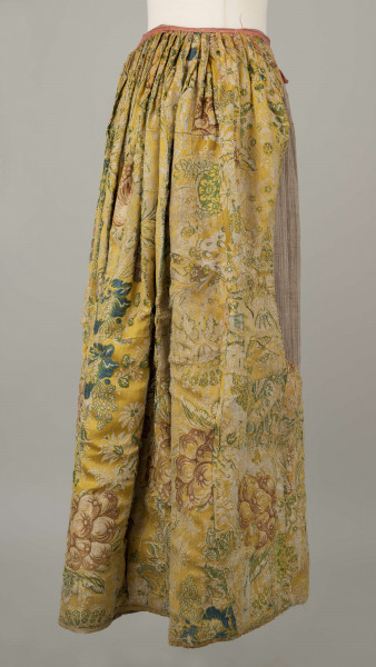 E/880/ML - Spódnica wykonana z brokatu, różnobarwna w kwiaty. Przewaga koloru złotego. Posiada lnianą podszewkę. Na przodzie wstawione lniane płótno w pasy. Noszona przez zamężne kobiety, bogate mieszczki tarnogrodzkie.