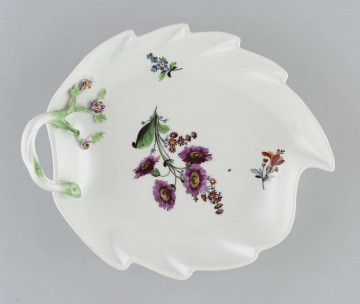 Paterka w kształcie liscia o brzegu podniesionym, wykrojonym faliście, z uchem w formie gałązki przechodzącej na dno, gdzie zdobią ją plastyczne kwiaty. Pośrodku malowany wielobarwny bukiet kwiatów z purpurowymi margerytkami, obok dwie drobne gałązki kwiatowe.
 