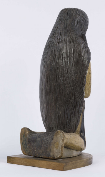 E/6353/ML - Figura drewniana, zakomponowana na postumencie, polichromowana. Postać klęcząca przedstawia św. Onufrego. Twarz płaska, trójkątna, głęboko osadzone oczy, czarne źrenice. Szerokie łuki brwiowe łączą się z wydatnym prostym nosem. Wystające kości jarzmowe. Małe usta otacza bujny zarost: broda i wąsy łączące się z bujnymi włosami, otaczającymi całą postać – na podobieństwo płaszcza. Ręce zgięte w łokciach, uniesione ku górze, łączą się końcami palców w geście modlitwy. W nieproporcjonalnie dużych dłoniach biały różaniec zakończony dużym krzyżem. Nogi masywne z dużymi płaskimi stopami. Prawą dłonią podtrzymuje sękaty kostur. W partii pasa przepasany powrozem z węzłami. 