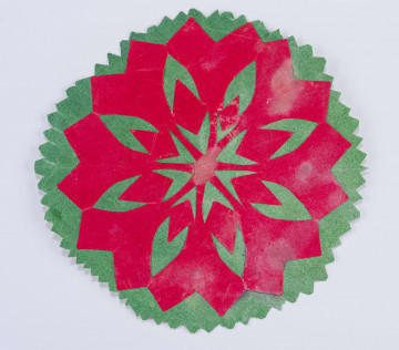 Wycinanka naklejona z zielonego i czerwonego papieru. Tło zielone o kształcie 8boku. Z czerwonego papieru wycięta 16ramienna o ramionach ażurowanych w serduszka i gwiazdkę.

