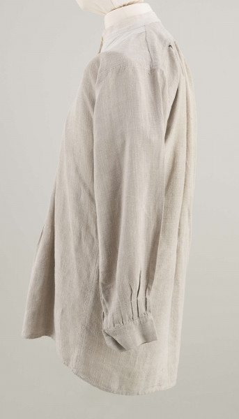 E/9858/ML - Koszula męska z lnianego samodziałowego płótna tkanego splotem prostym, szyta na maszynie. Krój z karczkiem. Wycięcie koło szyi wykończone stójką z białego płótna zapinana na jeden guziczek. Rozcięcie na przodzie o dł. 26 cm zapinane na dwa guziczki, wykończone fałdem o szer. 4,5 cm. Gors naszyty jest cienkim białym płótnem. Rękawy długie, krojone, razem z włokami dołem wzbogacone ośmioma zakładkami ujęte w mankiet o dł. 24 cm szer. 4 cm zapinany na guziczek.