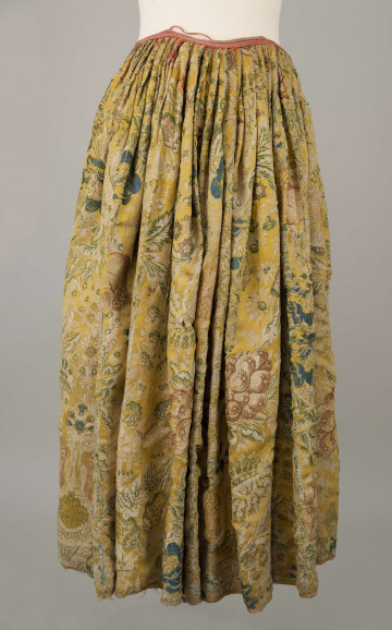 E/880/ML - Spódnica wykonana z brokatu, różnobarwna w kwiaty. Przewaga koloru złotego. Posiada lnianą podszewkę. Na przodzie wstawione lniane płótno w pasy. Noszona przez zamężne kobiety, bogate mieszczki tarnogrodzkie.