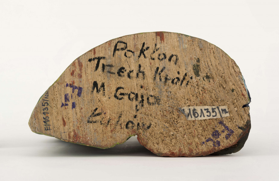 Rzeźba z drewna lipowego, technika strugania, polichromowana farbami plakatowymi. Na postumencie w kształcie nieregularnego owalu o wym. 23 x 13 x 1,5 cm, w kolorze seledynowym, zakomponowane zostały cztery postacie. W głębi z lewej strony postać króla (wys. 38 cm) w granatowej długiej szacie i zielonym płaszczu, z okrągłym kołnierzem. Król w lewej podniesionej ręce trzyma złotą koroną, w prawej – srebrny dzbanek. Z prawej strony postać Matki Boskiej (wys. 38,5 cm) z Dzieciątkiem (wys. 17 cm) w kremowej sukience, na prawym ręku. MB w czerwonej długiej sukni, zielonym płaszczu i niebieskiej chustce na głowie. Przed MB z lewej strony klęczy król (wys. 24,5 cm) w czerwonym płaszczu i czarnej sukni, który w rękach trzyma złotą szkatułkę. Z prawej strony klęczy król (wys. 28,5 cm) w granatowym płaszczu o niebieskim podbiciu i mankietach, brązowych spodniach, granatowych butach sięgających do połowy łydki. Na głowie ma złotą koronę na czerwonej czapce, otoczonej białym zawojem. W lewej ręce trzyma złotu kielich. 