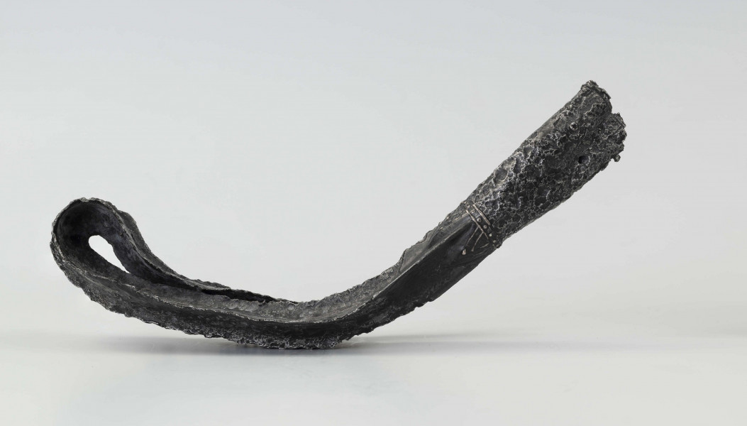 Żelazny grot broni drzewcowej zdobiony wyjątkową, srebrną inkrustacją jest częścią uzbrojenia włożonego do grobu ciałopalnego wojownika z początku III w. n.e. 
Grób przedstawiciela ludności kultury przeworskiej został odkryty przypadkowo w 1959 roku. 
Oprócz trzech grotów, pochówkowi wojownika towarzyszyły: żelazne umbo, dwie ostrogi, tok brązowy (prawdopodobnie okucie drzewca oszczepu) a także żelazny miecz z miedziana inkrustacją wyobrażającą rzymskich bogów. Pochowany na terenie obecnej wsi Podlodów wojownik należał do elity wojskowej przedstawicieli kultury przeworskiej. Liść grotu jest smukły i długi, a u podstawy cylindrycznej i krótkiej tulejki znajduje się żeberko. Na obydwu częściach grotu znajdują się zdobienia inkrustowane srebrem - znaki o znaczeniu symbolicznym: trójkąty sferyczne, punkty, podwójne widełki. Przypominają one symbole religijne (ewentualnie znaki magiczne lub własnościowe) - tamgi. Niektórzy badacze zakładają, że mogły one zostać przejęte przez Sarmatów. 
Wymiary dodatkowe: szer. 4,0 cm 