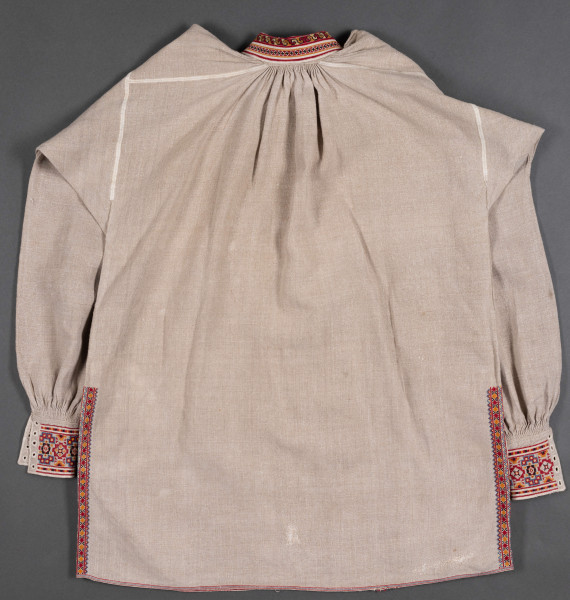 Koszula męska z wykładanym kołnierzem. Wykonana z lnianego płótna. Haftowana nićmi w kolorach: czerwonym, czarnym, żółtym i szafirowym.