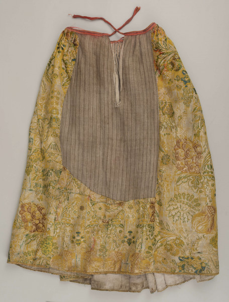 E/880/ML - Spódnica wykonana z brokatu, różnobarwna w kwiaty. Przewaga koloru złotego. Posiada lnianą podszewkę. Na przodzie wstawione lniane płótno w pasy. Noszona przez zamężne kobiety, bogate mieszczki tarnogrodzkie.