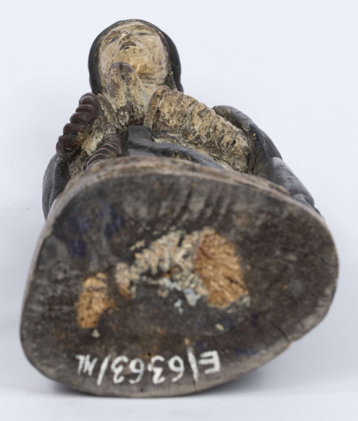 E/6363/ML - Rzeźba z drewna lipowego, polichromowana farbą olejną. Zakomponowana w jednym kawałku drewna na postumencie o formie owalnej z płaskorzeźbionym motywem dwóch skrzyżowanych gałęzi. Postać stojąca przedstawia Matkę Boską Różańcową. Twarz owalna, głęboko osadzone oczy, prosty i szeroki nos, małe pełne usta. Ręce zgięte w łokciach: duże dłonie złożone do modlitwy. Na przedramieniu prawej ręki brązowy różaniec o płaskich paciorkach, zakończony dużym krzyżem. Postać odziana w białą prostą suknię, gładko wykończoną pod szyją i przewiązaną granatową szarfą. Na głowie granatowa szata spełniająca jednocześnie rolę peleryny spływającej z ramion ku dołowi i spowijającej całą postać.