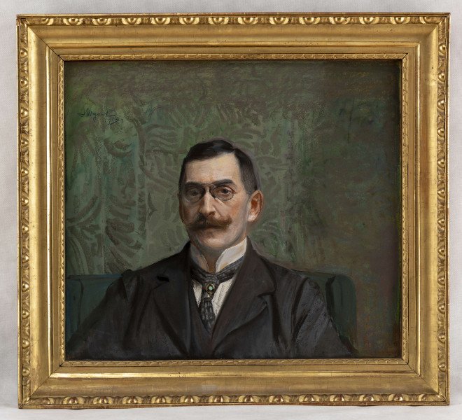 Popiersie mężczyzny w średnim wieku, nieco na lewo od osi, na tle zielonej ściany ze stylizowanym, dekoracyjnym wzorem. Głowa nieznacznie w lewo. Twarz owalna, wypukłe, wąskie czoło, duże głęboko osadzone oczy, mocno zarysowne łuki brwiowe, nos z 