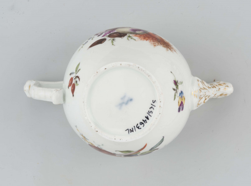 Imbryk kulisty lekko zwężony ku dołowi, wokół wylewu zdobiony plastyczną plecionka w typie Alt-Ozier. Dziobek rurkowy zakończony rozwartym smoczym pyskiem podkreślonym plastycznym liściem akantu. Ucho rokokowe w kształcie litery 