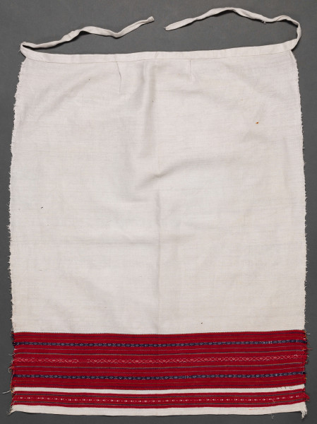 Fartuszek lniany ozdobiony u dołu haftem tkackim, zw. perebory w kolorze czerwono-granatowym.