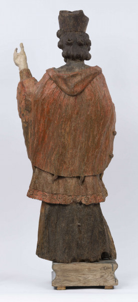 E/16816/ML - Rzeźba drewniana, pełna, polichromowana, przedstawiająca św. Jana Nepomucena. Kompozycja frontalna. Postać stojąca w kontrapoście – prawa noga zgięta i wysunięta do przodu. Sylwetka przechylona na prawo. Lewa ręka zgięta w łokciu i wysunięta do przodu. Prawa zgięta, uniesiona do góry. Brak atrybutów (krzyża i palmy) w dłoniach.
Postać ubrana w sutannę, komżę drapowaną w fałdy i zakończoną koronką, płaszcz z kapturem. Ślady złoceń na partii ubrania. Głowa skierowana na prawo. Twarz podłużna (kolor kremowy), usta proste, oczy z zaznaczonymi na ciemno tęczówkami, nos prosty, lekko zaznaczone kości policzkowe. Wolutowe pukle brody i włosów, symetryczne. Na głowie ciemnobrązowy biret. Stopy wystające spod sutanny.

Konserwacja: 2001 r.