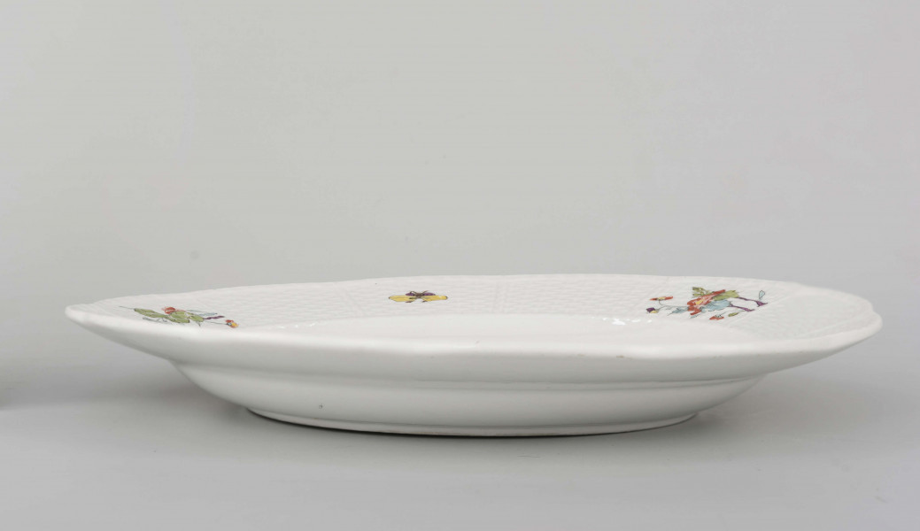 Talerz okrągły o falistym brzegu. Dno płaskie, kołnierz ukośnie odchylony pokryty reliefem plecionkowym z tzw. splotem Sułkowskiego, z podziałęm na 12 pól. Dekoracja malarska rozmieszczona nieregularnie na dnie półmiska: krzak peonii z chrabąszczem majowym, skrzydlaty smok i lecąca czapla. Na kołnierzu drobne gałązki kwiatowe na przemian z motylami. Barwy: błękit, czerwień, zieleń groszkowa i turkusowa, purpura, żółcienie, brąz i czerń.
Na spodzie sygnatura kobaltowa pod szkliwem: dwa skrzyżowane miecze.