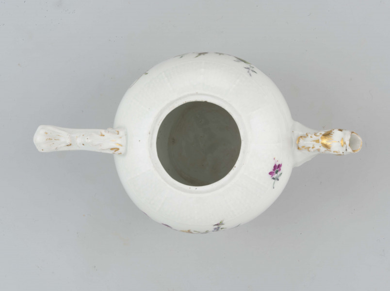 Imbryk kulisty lekko zwężony ku dołowi, wokół wylewu zdobiony plastyczną plecionka w typie Alt-Ozier. Dziobek rurkowy zakończony rozwartym smoczym pyskiem podkreślonym plastycznym liściem akantu. Ucho rokokowe w kształcie litery 