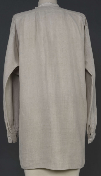 E/7980/ML - Koszula męska z lnianego, szarego płótna. Szyta ręcznie. Kołnierzyk to wąska oszewka z bawełnianego płótna. Z przodu rozcięcie zapinane na 3 guziczki wzmocnione plisą z podwójnego kawałka płótna. Rękawy długie, ujęte w mankiet, zapinany na guziczek. Pod pachami wszyte prostokątne kawałki tkaniny, zw. tokami.