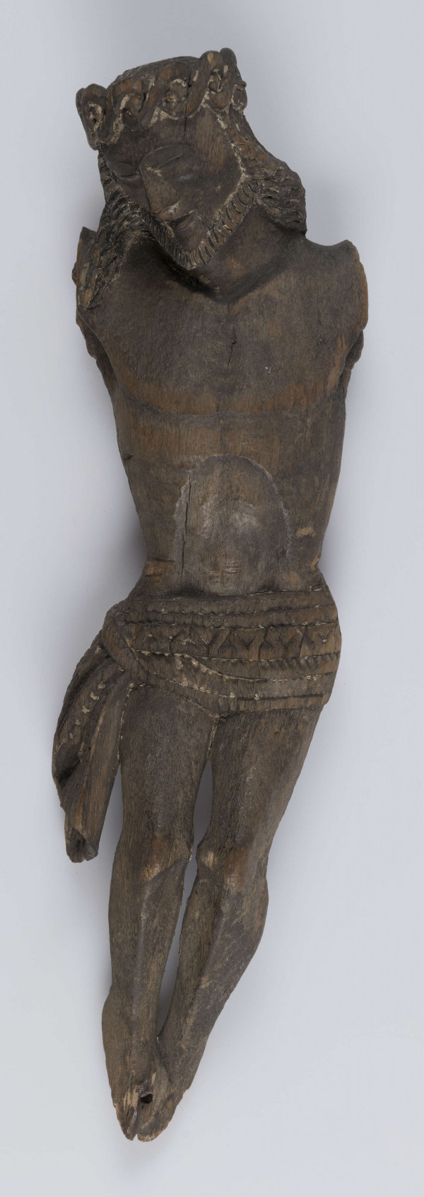 E/342/ML - Chrystus Ukrzyżowany. Stan rzeźby zły. Brak rąk i stóp. Głowa pochylona w prawo. Rysy twarz wyraziste, ostre. Głowę oplata korona cierniowa spleciona z wypukłych wałeczków. Włosy okalają twarz i opadają na ramiona. Krótka bródka, podkreślona pionowymi żłobieniami okala brodę. Piersi wyodrębnione półkolistą linią. Zaakcentowana środkowa część brzucha. Perizonium stanowi prosty, krótki płat materiału, który jest związany na prawym biodrze na węzeł, a końce jego opadają luźno. Powierzchnię perizonium wypełnia rzeźbiony ornament. Nogi proste. Podkreślone mięśnie ud i łydek. Stopy złączone.