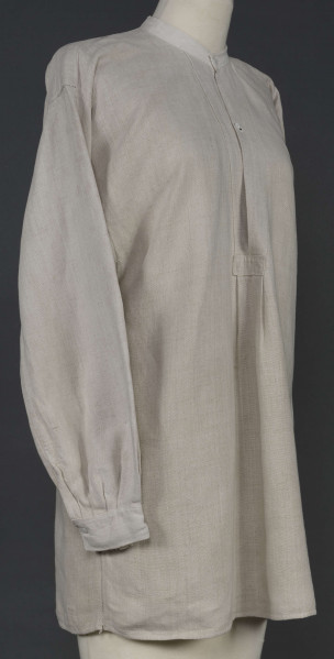 E/7980/ML - Koszula męska z lnianego, szarego płótna. Szyta ręcznie. Kołnierzyk to wąska oszewka z bawełnianego płótna. Z przodu rozcięcie zapinane na 3 guziczki wzmocnione plisą z podwójnego kawałka płótna. Rękawy długie, ujęte w mankiet, zapinany na guziczek. Pod pachami wszyte prostokątne kawałki tkaniny, zw. tokami.