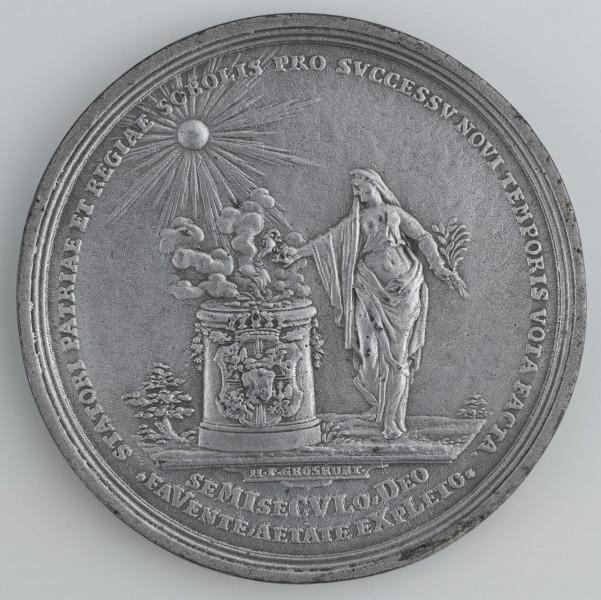 N/1557/ML - AV. Z lewej postać króla w rzymskim stroju z cyfrą L w lewej ręce. Obok, z prawej postać młodzieńca opartego o snopek z boża, z rogiem obfitości. Obok dziecko z girlandą. W otoku napis: (zob. w zakładce 