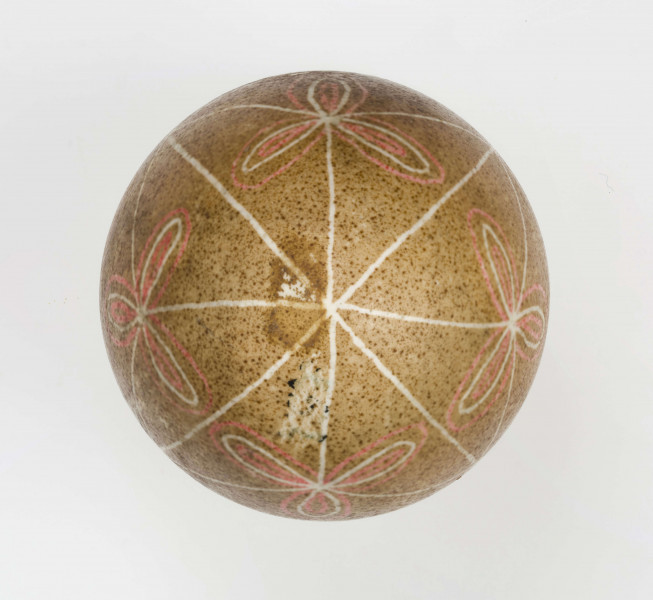 Technika batik. Podział podłużny na 4 części, podział poprzeczny na 2 części. Motyw trikwert. Barwa tła brązowa, barwa motywu biała i czerwona.