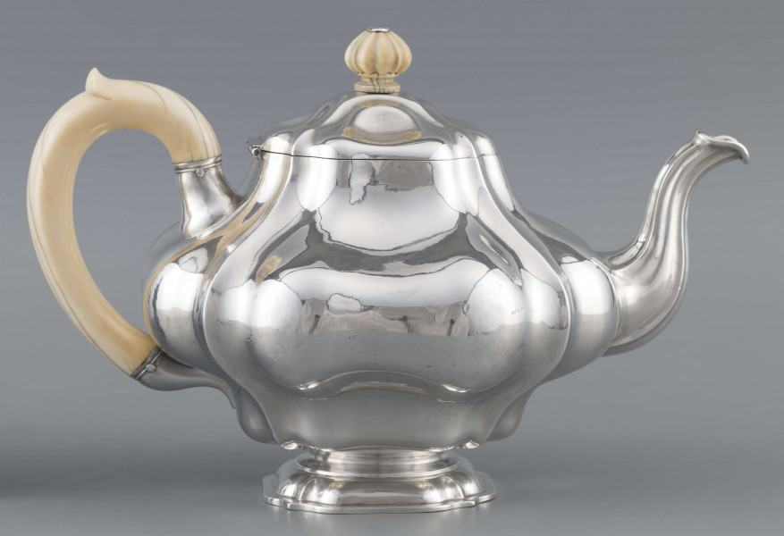 S/Mt/500/ML - Korpus silnie wybrzuszony w części środkowej, puklowany pionowo, profile przechodzą na pokrywke w formie wieczka na zawiasie. Stopa kwadratowa wielolistna, wylew w formie dzióbka, ucho kościane osadzone w dwóch tulejkach,
uchwyt na pokrywce kościany, profilowany. Wnetrze złocone.
Na spodzie stopy sygnatura:
- 