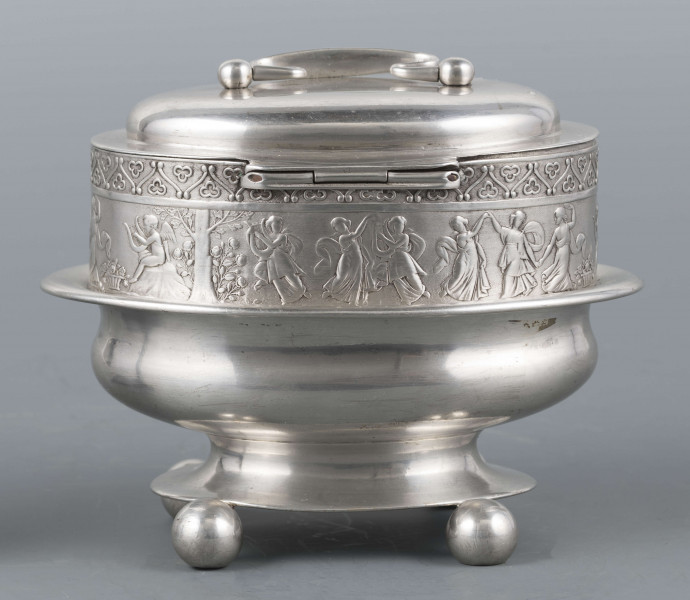 S/Mt/363/ML - Cukiernica owalnana niskiej stopie z czterema kulistymi nóżkami, z pokrywką w formie wieczka.
Podzielona na dwie części : 
- część dolna lekko wybrzuszona, o gładkiej powierzchni, kończy się w połowie wysokości wywiniętym kołnierzem; - część górna prosta uformowana jest z moletowanej taśmy, na której powtarza się trzykrotnie scenka antyczna: po rawej siedzący pod drzewem amorek gra na lirze, po lewej stoi grająca na lirze kobieta, pomiędzy nimi tańczą trzy inne.Górną krzwędź obiega pas stylizowanych neogotyckich trójliści.