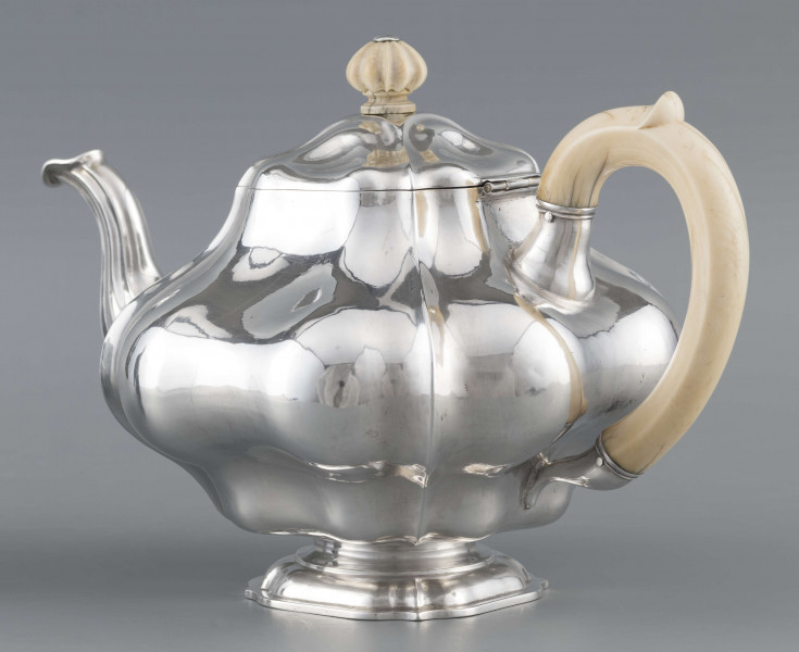 S/Mt/500/ML - Korpus silnie wybrzuszony w części środkowej, puklowany pionowo, profile przechodzą na pokrywke w formie wieczka na zawiasie. Stopa kwadratowa wielolistna, wylew w formie dzióbka, ucho kościane osadzone w dwóch tulejkach,
uchwyt na pokrywce kościany, profilowany. Wnetrze złocone.
Na spodzie stopy sygnatura:
- 