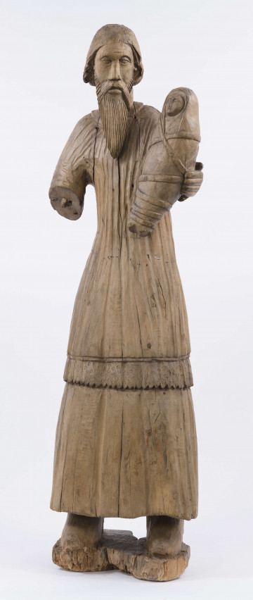 E/1958/ML - Rzeźba z drewna lipowego, niepolichromowana. Przedstawia postać św. Józefa z Dzieciątkiem Jezus na ręku. Postać świętego w dwóch sukniach, jednej spodniej, długiej sięgającej do kostek, gładkiej oraz wierzchniej sięgającej do kolan, zakończonej falbaną. Prawa ręka świętego powyżej łokcia jest ułamana. Na lewej nieproporcjonalnie krótkiej ręce, Św. Józef trzyma Dzieciątko Jezus , spowite w powijaki i przewiązane tasiemkami. Twarz świętego pociągła, o wyrazistych rysach, długiej szpiczastej brodzie i opadających wąsach. Włosy sięgają karku. Postać zakomponowana na prostokątnej podstawie, o wys. 4 cm, lekko uszkodzonej. 

Konserwacja: 1985 r.