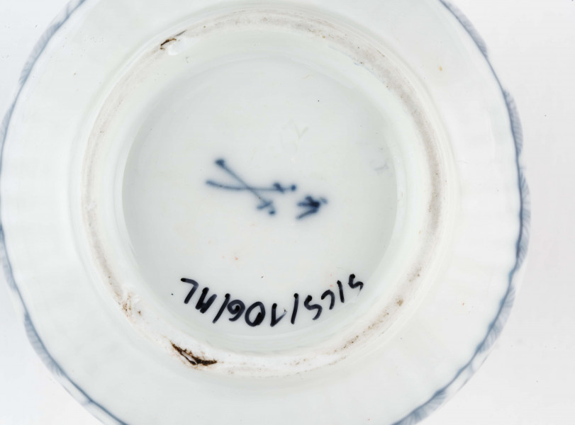 Dzbanek gruszkowaty na niskiej pierścieniowatej podstawie, ucho wolutowe, wylew trókątny, powierzchnia drobno kanelowana. Malowany podszkliwnie błękitem kobaltowym we wzór suchych kwiatów (kocanka), poniżej brzegu górnego na zewnatrz i wewnątrz malowana cienka obwódka, na dnie brzegu uszka gałązka. 
