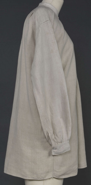 E/7980/ML - Koszula męska z lnianego, szarego płótna. Szyta ręcznie. Kołnierzyk to wąska oszewka z bawełnianego płótna. Z przodu rozcięcie zapinane na 3 guziczki wzmocnione plisą z podwójnego kawałka płótna. Rękawy długie, ujęte w mankiet, zapinany na guziczek. Pod pachami wszyte prostokątne kawałki tkaniny, zw. tokami.