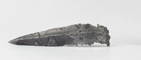 Żelazny grot oszczepu z ostrym żeberkiem środkowym, zgięty rytualnie (złamany w miejscu zgięcia). Grot stanowi element wyposażenia ciałopalnego pochówku złożonego prawdopodobnie w popielnicy. Odkrycia dokonano w 1959 roku przypadkowo w czasie prac rolnych. Oprócz trzech grotów, pochówkowi wojownika towarzyszyły: żelazne umbo, dwie ostrogi, tok brązowy (prawdopodobnie okucie drzewca oszczepu) a także żelazny miecz z miedziana inkrustacją wyobrażającą rzymskich bogów. Pochowany na terenie obecnej wsi Podlodów wojownik należał do elity wojskowej przedstawicieli kultury przeworskiej.