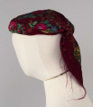 E/516/ML - Czepek mężatki. Denko wewnętrzne wykonane z plecionej siatki zielonej. Z wierzchu chustka fabryczna koloru ciemnoczerwonego w kwiaty wiązana na tekturowej obręczy. Końce chustki zwisają do tyłu.
