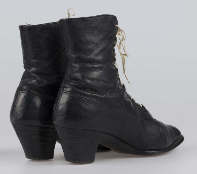 E/11811/ML - Buty odświętne, z czarnej licowej skóry. Wewnątrz płócienna podszewka. Obcas słupowaty wys. 5 cm. Podeszwy ze skóry. Cholewka wys. 10 cm, dopasowana do nogi, z przodu sznurowana. Nosek zwężony, na końcu ścięty. Wykrój podeszew w obu butach identyczny – lewy równa się prawemu.