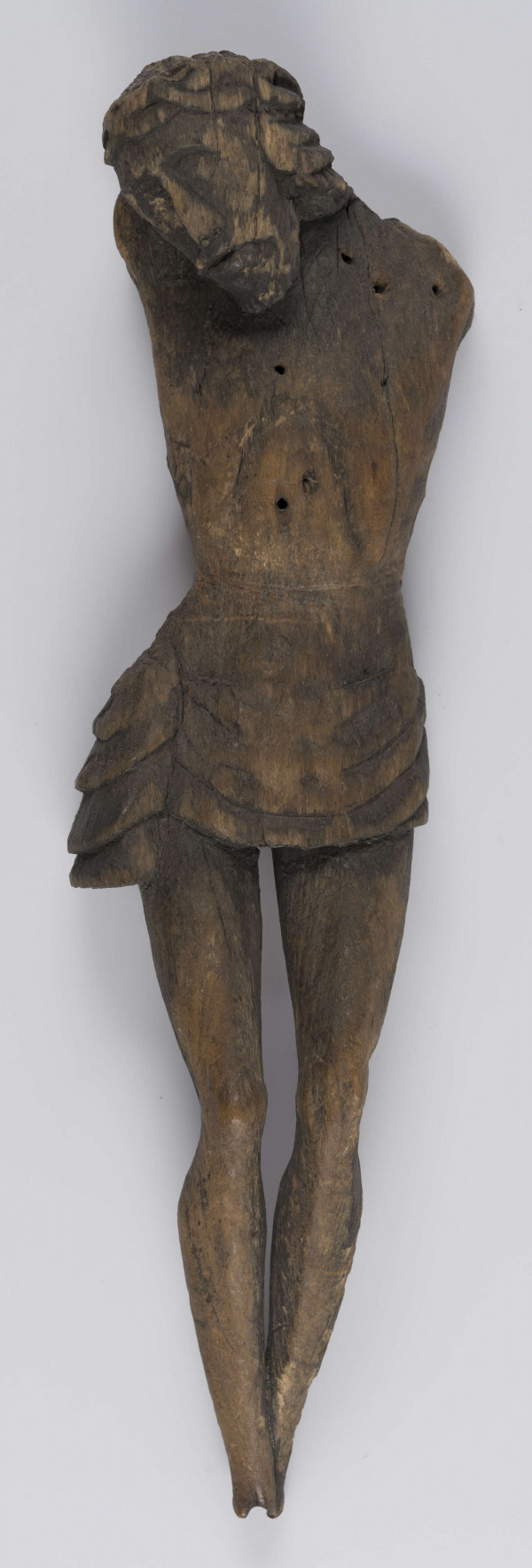 E/336/ML - Chrystus Ukrzyżowany. Stan rzeźby zły, brak rąk i stóp. Głowa lekko pochylona w prawo. Twarz o wyrazistych rysach. Na głowie korona cierniowa spleciona z wałeczków, luźno. Perizonium podkreślone łukowatymi żłobieniami. Z prawej strony płat materiału stanowiący perizonium - związany w fantazyjny węzeł. Nogi proste. Wyodrębnione uda, kolana i łydki. Stopy złączone.
