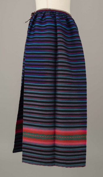 E/6813/ML - Fartuszek wełniany tkany w kolorowe wąskie pasy w kolorze: granatowym, niebieskim, fioletowym, czarnym i amarantowym z szerokim pasem o wiązce kolorystycznej: amarantowy, czerwony, zielony. Przymarszczony i wszyty w płócienny pasek z troczkami.