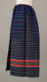 E/6813/ML - Fartuszek wełniany tkany w kolorowe wąskie pasy w kolorze: granatowym, niebieskim, fioletowym, czarnym i amarantowym z szerokim pasem o wiązce kolorystycznej: amarantowy, czerwony, zielony. Przymarszczony i wszyty w płócienny pasek z troczkami.