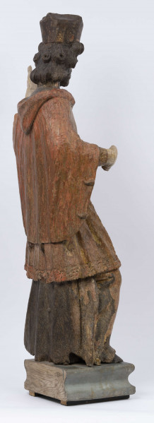 E/16816/ML - Rzeźba drewniana, pełna, polichromowana, przedstawiająca św. Jana Nepomucena. Kompozycja frontalna. Postać stojąca w kontrapoście – prawa noga zgięta i wysunięta do przodu. Sylwetka przechylona na prawo. Lewa ręka zgięta w łokciu i wysunięta do przodu. Prawa zgięta, uniesiona do góry. Brak atrybutów (krzyża i palmy) w dłoniach.
Postać ubrana w sutannę, komżę drapowaną w fałdy i zakończoną koronką, płaszcz z kapturem. Ślady złoceń na partii ubrania. Głowa skierowana na prawo. Twarz podłużna (kolor kremowy), usta proste, oczy z zaznaczonymi na ciemno tęczówkami, nos prosty, lekko zaznaczone kości policzkowe. Wolutowe pukle brody i włosów, symetryczne. Na głowie ciemnobrązowy biret. Stopy wystające spod sutanny.

Konserwacja: 2001 r.