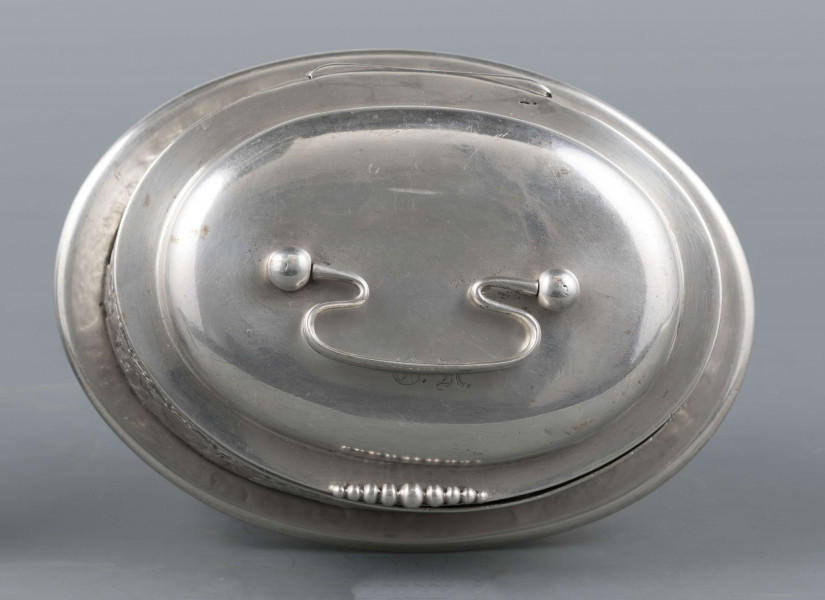 S/Mt/363/ML - Cukiernica owalnana niskiej stopie z czterema kulistymi nóżkami, z pokrywką w formie wieczka.
Podzielona na dwie części : 
- część dolna lekko wybrzuszona, o gładkiej powierzchni, kończy się w połowie wysokości wywiniętym kołnierzem; - część górna prosta uformowana jest z moletowanej taśmy, na której powtarza się trzykrotnie scenka antyczna: po rawej siedzący pod drzewem amorek gra na lirze, po lewej stoi grająca na lirze kobieta, pomiędzy nimi tańczą trzy inne.Górną krzwędź obiega pas stylizowanych neogotyckich trójliści.