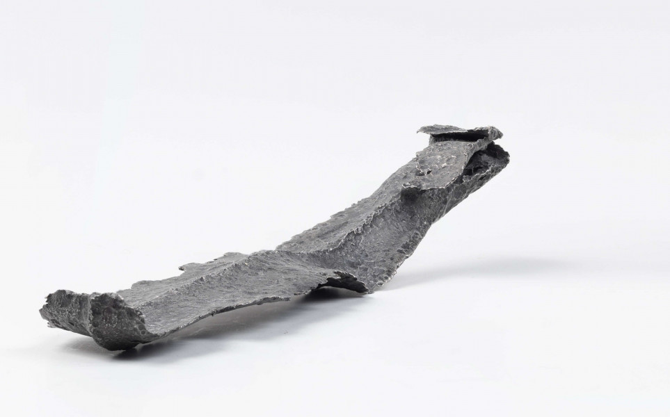 Żelazny grot oszczepu z ostrym żeberkiem środkowym, zgięty rytualnie. Grot stanowi element wyposażenia ciałopalnego pochówku złożonego prawdopodobnie w popielnicy. Odkrycia dokonano w 1959 roku przypadkowo w czasie prac rolnych. Oprócz trzech grotów, pochówkowi wojownika towarzyszyły: żelazne umbo, dwie ostrogi, tok brązowy (prawdopodobnie okucie drzewca oszczepu) a także żelazny miecz z miedziana inkrustacją wyobrażającą rzymskich bogów. Pochowany na terenie obecnej wsi Podlodów wojownik należał do elity wojskowej przedstawicieli kultury przeworskiej.