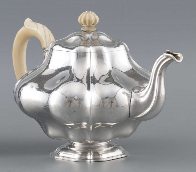 S/Mt/500/ML - Korpus silnie wybrzuszony w części środkowej, puklowany pionowo, profile przechodzą na pokrywke w formie wieczka na zawiasie. Stopa kwadratowa wielolistna, wylew w formie dzióbka, ucho kościane osadzone w dwóch tulejkach,
uchwyt na pokrywce kościany, profilowany. Wnetrze złocone.
Na spodzie stopy sygnatura:
- 