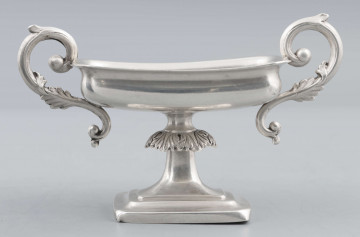 S/Mt/57/ML - Stopa prostokątna, wysklepiona, przechodząca w trzon z owalnym kapturkiem sztancowanym we wzór akantu. Czarka prostokatna o zaokrąglonych narożach i wywinietym brzegu, z dwoma uchami na krótszych bokach. Ucha wolutowe zdobione listkami. 