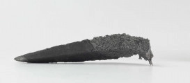 Żelazny grot oszczepu z ostrym żeberkiem środkowym, zgięty rytualnie (złamany w miejscu zgięcia). Grot stanowi element wyposażenia ciałopalnego pochówku złożonego prawdopodobnie w popielnicy. Odkrycia dokonano w 1959 roku przypadkowo w czasie prac rolnych. Oprócz trzech grotów, pochówkowi wojownika towarzyszyły: żelazne umbo, dwie ostrogi, tok brązowy (prawdopodobnie okucie drzewca oszczepu) a także żelazny miecz z miedziana inkrustacją wyobrażającą rzymskich bogów. Pochowany na terenie obecnej wsi Podlodów wojownik należał do elity wojskowej przedstawicieli kultury przeworskiej.