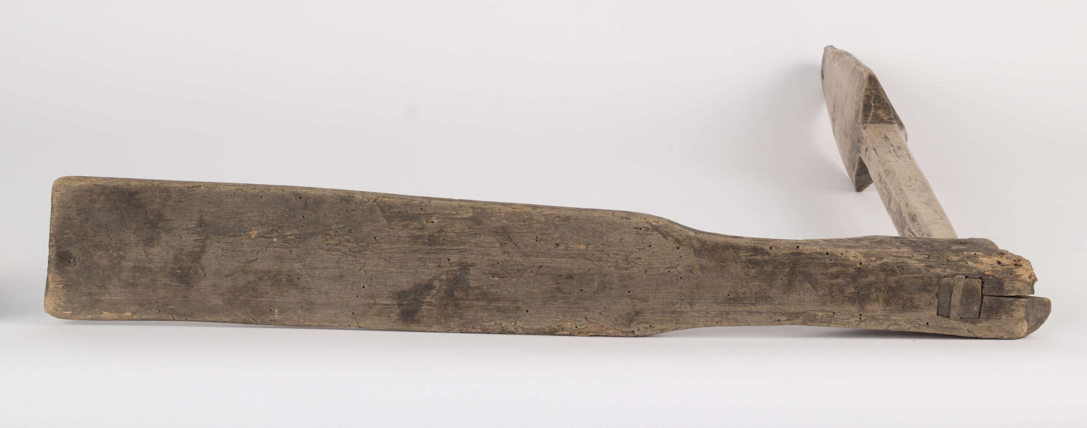 E/8397/ML - Przęślica łopatkowa z drewna. Składa się z cienkiej deski – przysiadki, w której przy jednym końcu osadzona jest pionowa beleczka zw. piórem, z nasadzonym od góry ruchomym krężlem w kształcie łopatki, zdobionej w ząbki.