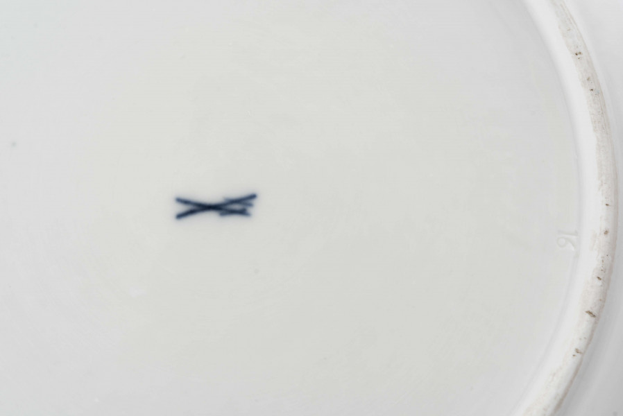 Talerz okrągły o falistym brzegu. Dno płaskie, kołnierz ukośnie odchylony pokryty reliefem plecionkowym z tzw. splotem Sułkowskiego, z podziałęm na 12 pól. Dekoracja malarska rozmieszczona nieregularnie na dnie półmiska: krzak peonii z chrabąszczem majowym, skrzydlaty smok i lecąca czapla. Na kołnierzu drobne gałązki kwiatowe na przemian z motylami. Barwy: błękit, czerwień, zieleń groszkowa i turkusowa, purpura, żółcienie, brąz i czerń.
Na spodzie sygnatura kobaltowa pod szkliwem: dwa skrzyżowane miecze.