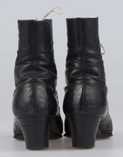 E/11811/ML - Buty odświętne, z czarnej licowej skóry. Wewnątrz płócienna podszewka. Obcas słupowaty wys. 5 cm. Podeszwy ze skóry. Cholewka wys. 10 cm, dopasowana do nogi, z przodu sznurowana. Nosek zwężony, na końcu ścięty. Wykrój podeszew w obu butach identyczny – lewy równa się prawemu.