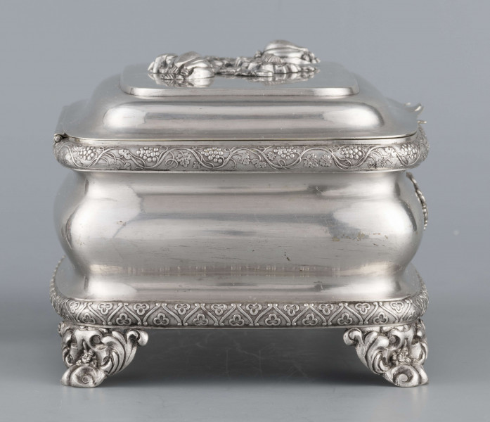 S/Mt/469/ML - Cukiernica prostokątna o zaokrągłonych narożach, profilowana, na czterech akantowych nóżkach. Brzeg dolny i górny obwiedzione półwałkiem zmoletowanej taśmy: u góry z wzorem winorośli, na dole - trójliścia.Brzeg wieczka fasetowany, z przodu lekko wywinięty tworzy uchwyt. Na wieczku nałożona półplastyczna plakieta w postaci  asymetrycznej gałązki kwiatowej. Szyld zamka stanowi sztancowana plakieta z motywem winorośli. Wnętrze złocone.
Na dnie sygnatura wypukła we wklęsłych ramkach:
- J.Suchocki
- w Lublinie
i punca z oznaczeniem próby 