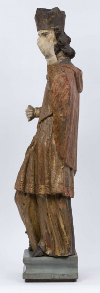 E/16816/ML - Rzeźba drewniana, pełna, polichromowana, przedstawiająca św. Jana Nepomucena. Kompozycja frontalna. Postać stojąca w kontrapoście – prawa noga zgięta i wysunięta do przodu. Sylwetka przechylona na prawo. Lewa ręka zgięta w łokciu i wysunięta do przodu. Prawa zgięta, uniesiona do góry. Brak atrybutów (krzyża i palmy) w dłoniach.
Postać ubrana w sutannę, komżę drapowaną w fałdy i zakończoną koronką, płaszcz z kapturem. Ślady złoceń na partii ubrania. Głowa skierowana na prawo. Twarz podłużna (kolor kremowy), usta proste, oczy z zaznaczonymi na ciemno tęczówkami, nos prosty, lekko zaznaczone kości policzkowe. Wolutowe pukle brody i włosów, symetryczne. Na głowie ciemnobrązowy biret. Stopy wystające spod sutanny.

Konserwacja: 2001 r.